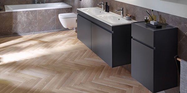 Eine schwarze Badewanne in einem Raum mit holzverkleideten Wänden und Boden.