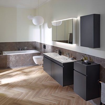 Eine schwarze Badewanne in einem Raum mit holzverkleideten Wänden und Boden.
