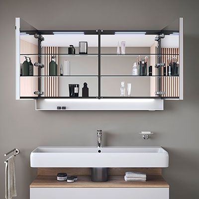 Ein Spiegelschrank mit integrierter Beleuchtung an den Seiten, der über einem Waschtisch hängt.